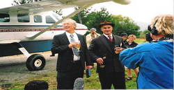 Dick Smith, flight logbook in left hand and champagne in right, enjoying a welcoming drink with Mr Lindsay Molloy.